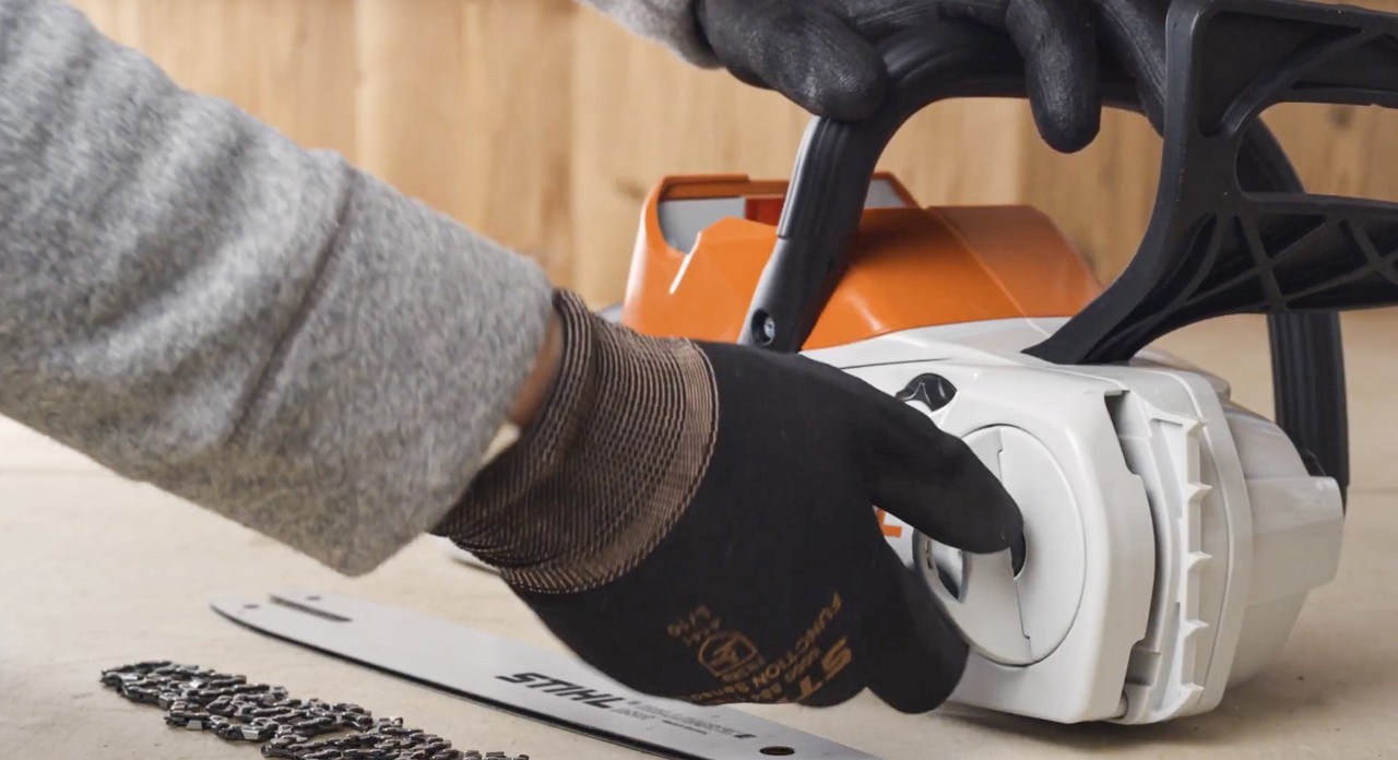 Una persona retira la tapa del piñón de cadena de una motosierra STIHL de batería MSA 120