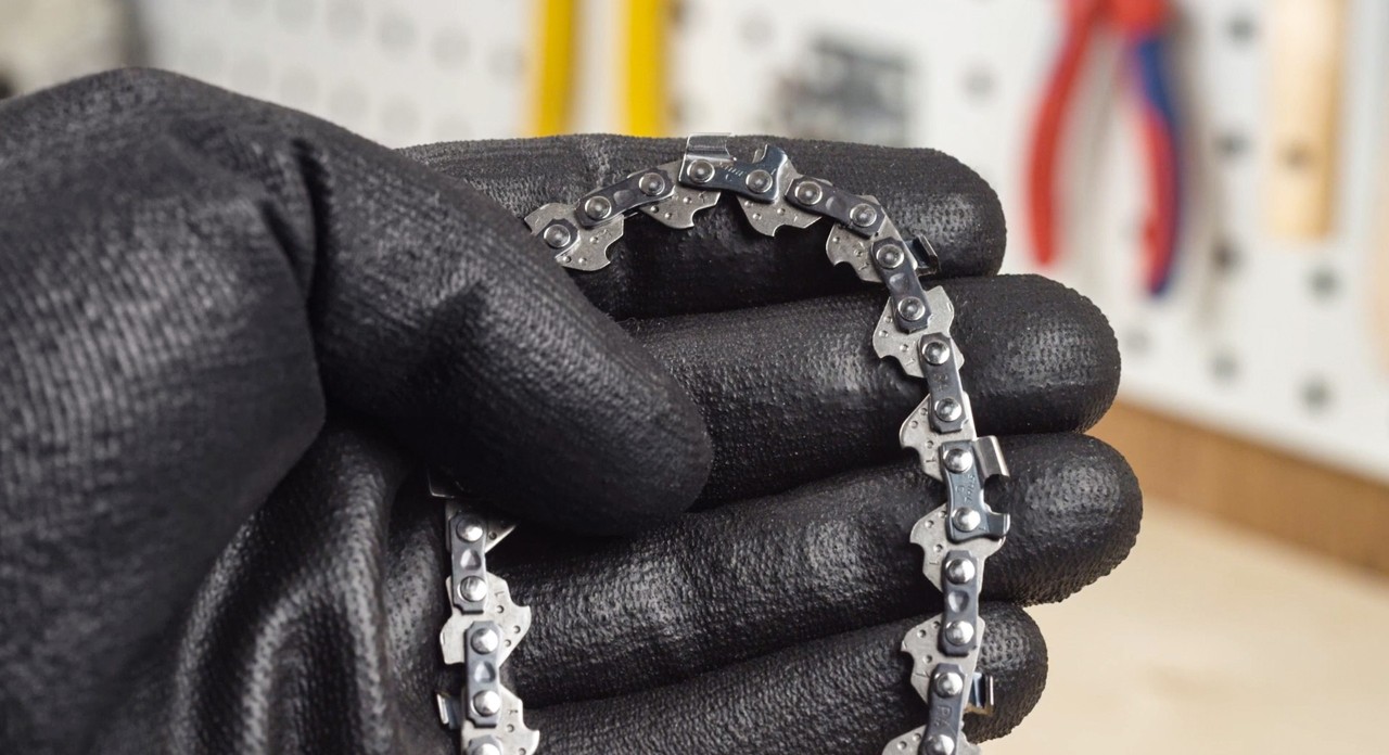 Primer plano de la cadena de una motosierra sujeta por una persona con guantes