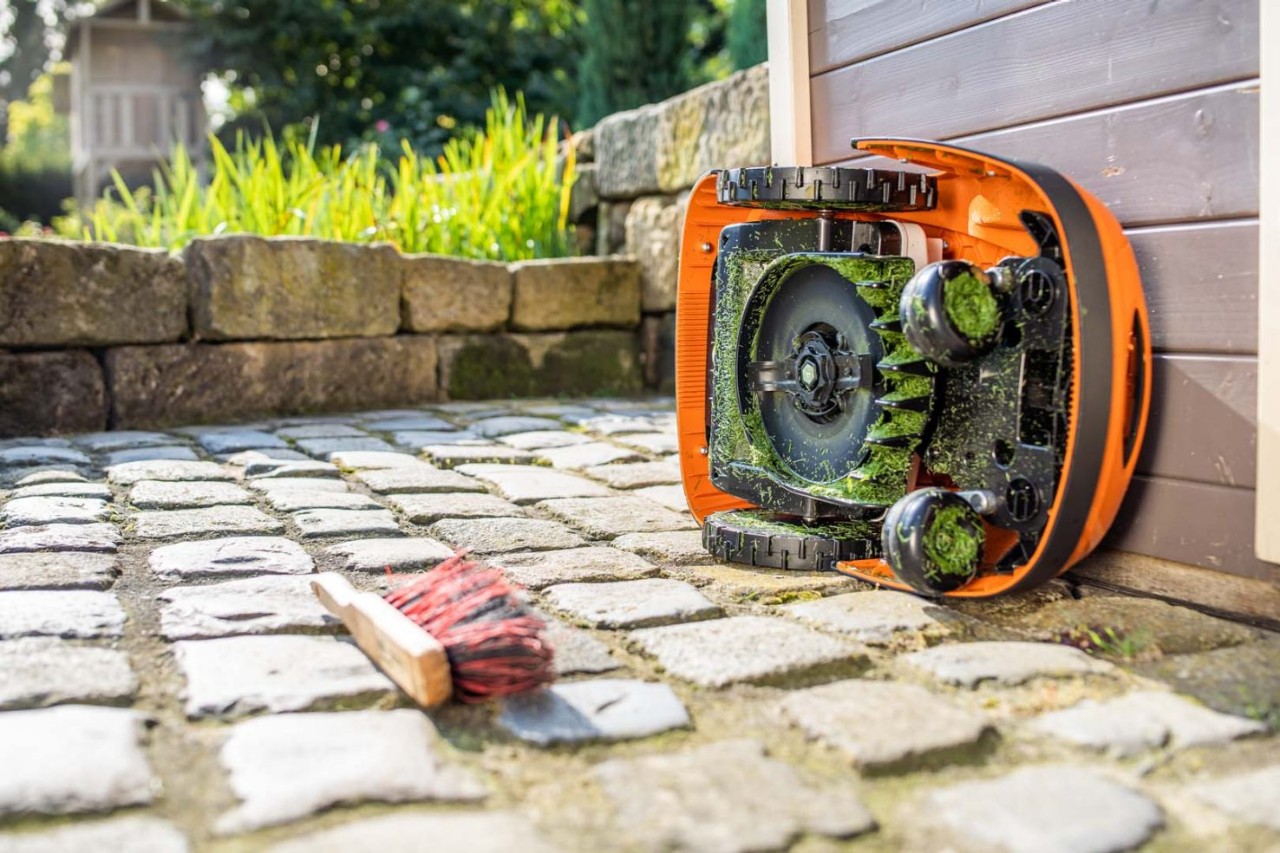 Un robot cortacésped STIHL iMOW® inclinado hacia un lado listo para la limpieza