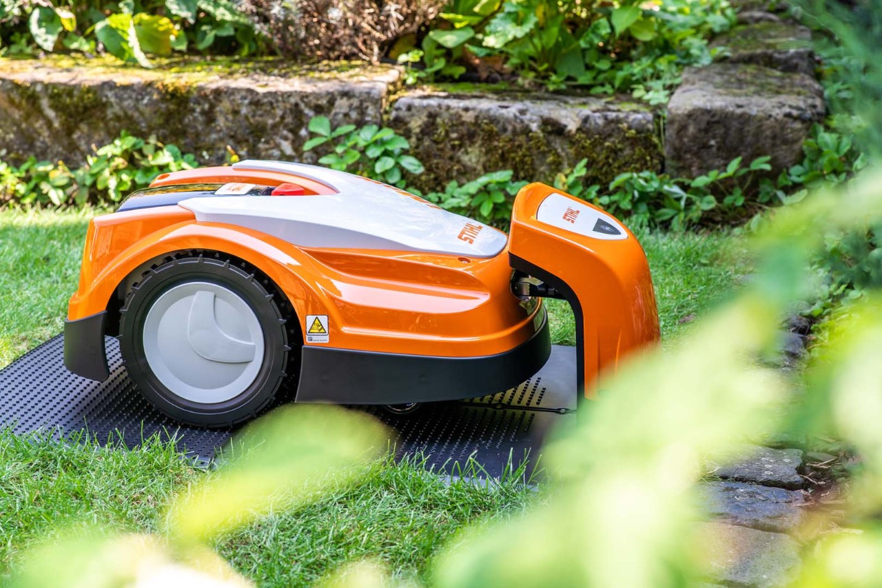 Un robot cortacésped STIHL iMOW® 422 en un jardín recargándose en su estación de carga