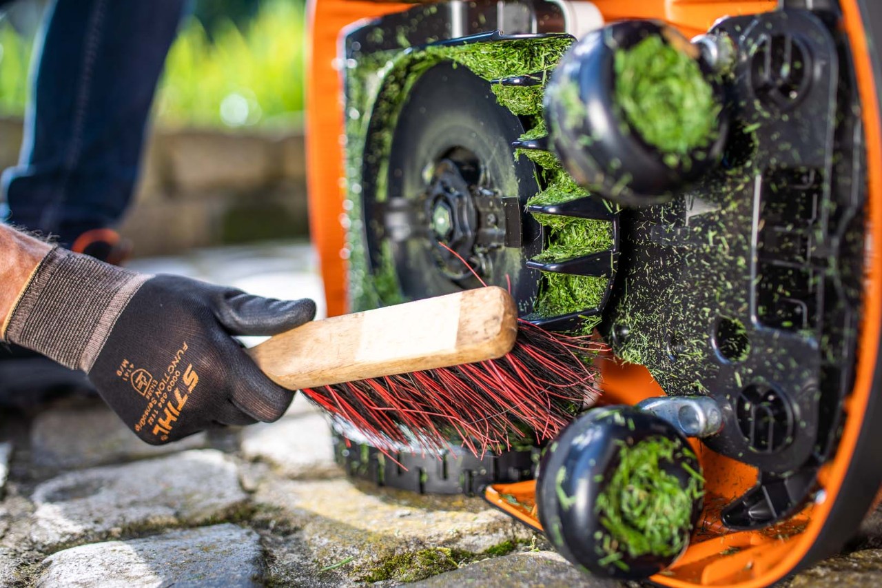 Limpieza de la parte inferior de un robot cortacésped STIHL iMOW® 422 con un cepillo