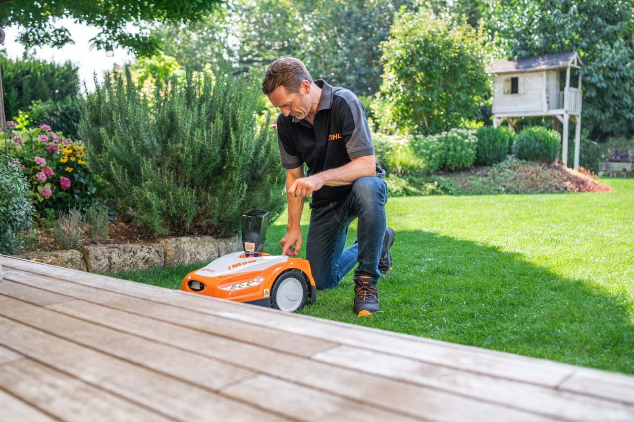 Un distribuidor STIHL configura el plan de corte dinámico de un robot cortacésped STIHL RMI 422 iMOW® en un césped verde