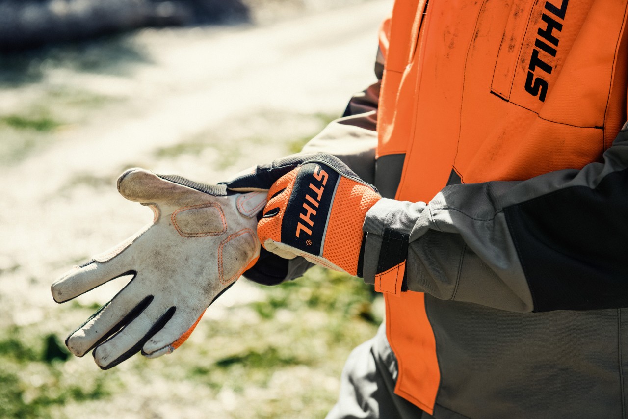 Primer plano de alguien poniéndose unos guantes de trabajo STIHL