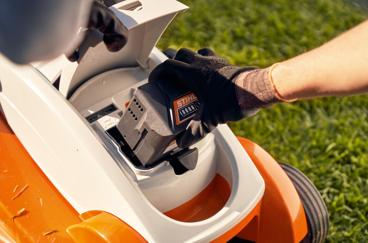 La persona quita la batería de un cortacésped de batería STIHL RMA 339C para almacenarlo para el invierno.