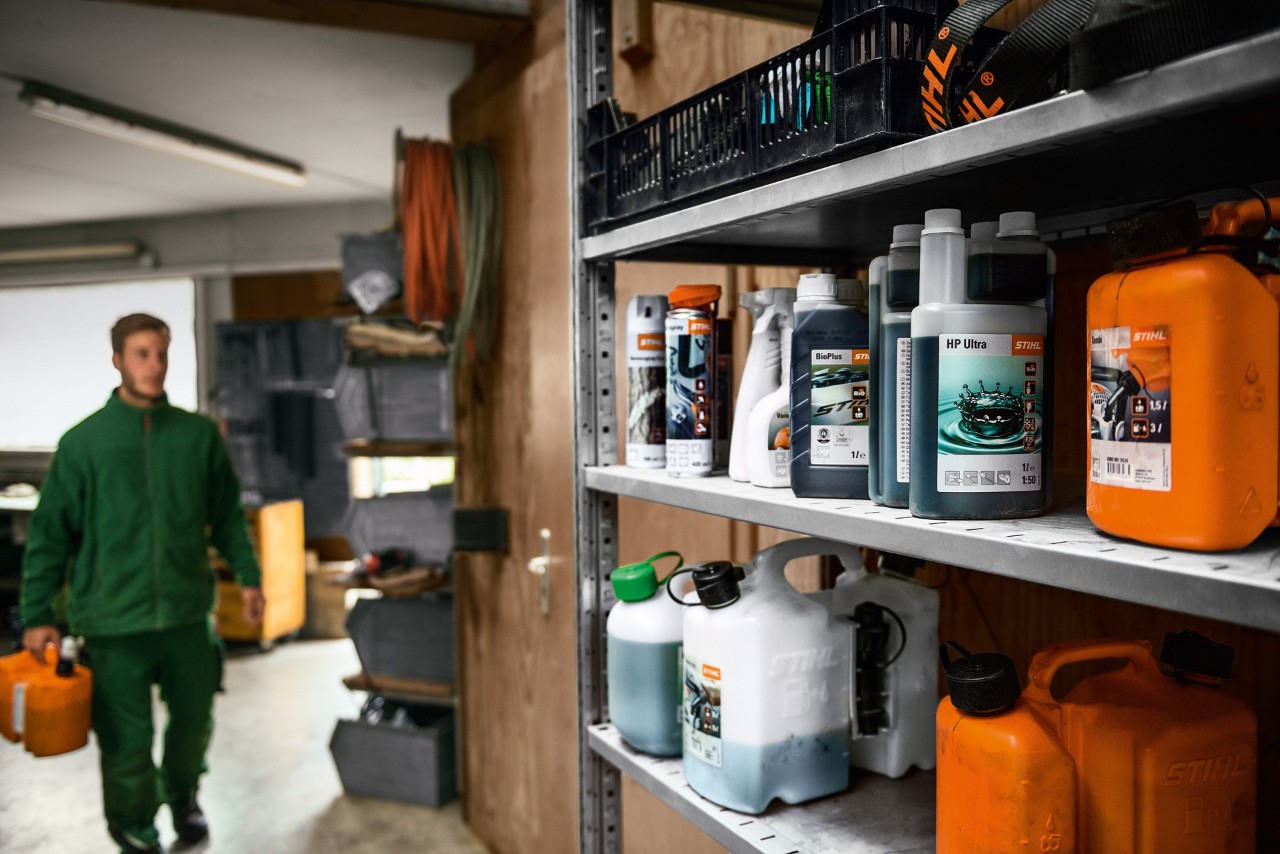 Un hombre en un garaje con lubricantes STIHL para repostar el cortacésped