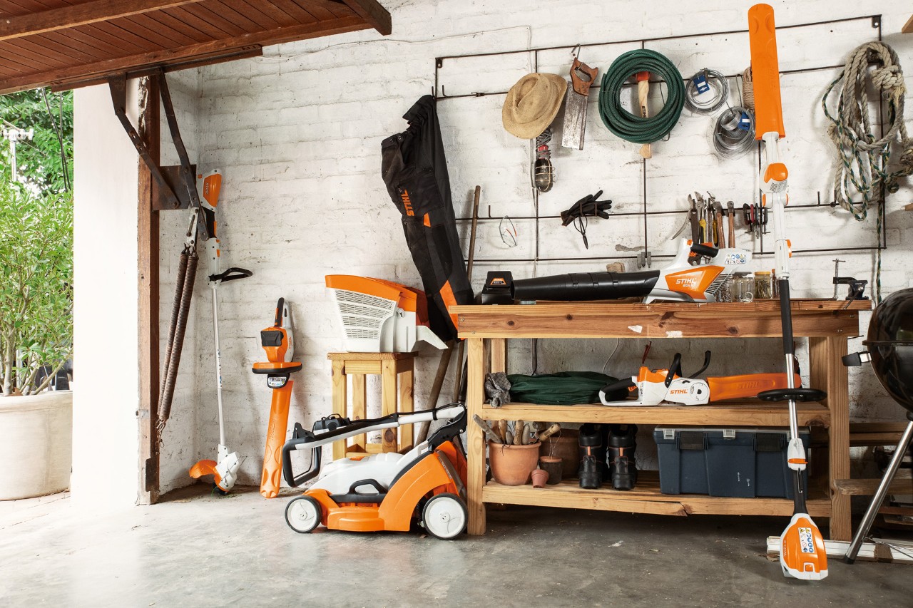 La motoguadaña de batería STIHL FSA 56 está colgada; al lado, los cortasetos  HSA 56 y HLA 56 y el cortacésped RMA 339