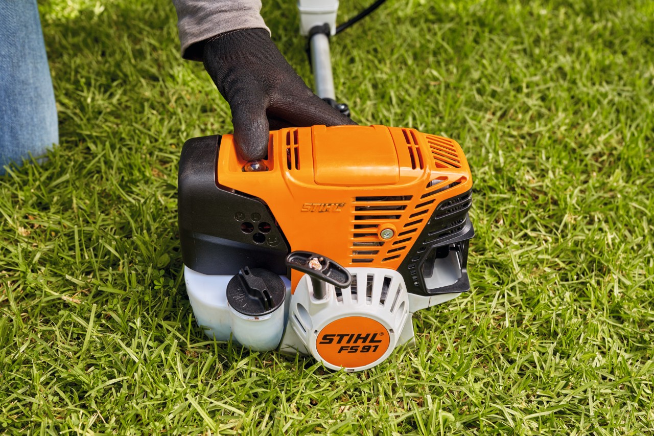 Un hombre presiona la bomba de combustible de la desbrozadora de gasolina STIHL FS 91 para arrancarla