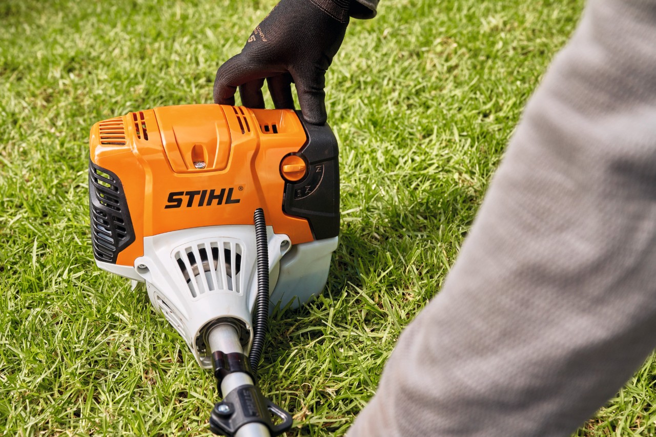 Un hombre presiona firmemente la desbrozadora de gasolina STIHL FS 91 contra el suelo