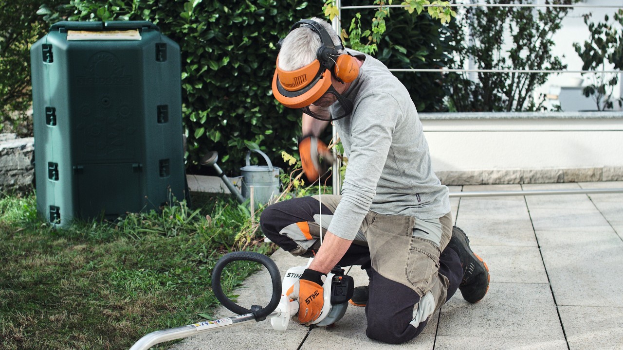 Persona con ropa de protección tira de la cuerda de arranque de la desbrozadora de gasolina STIHL FS 38