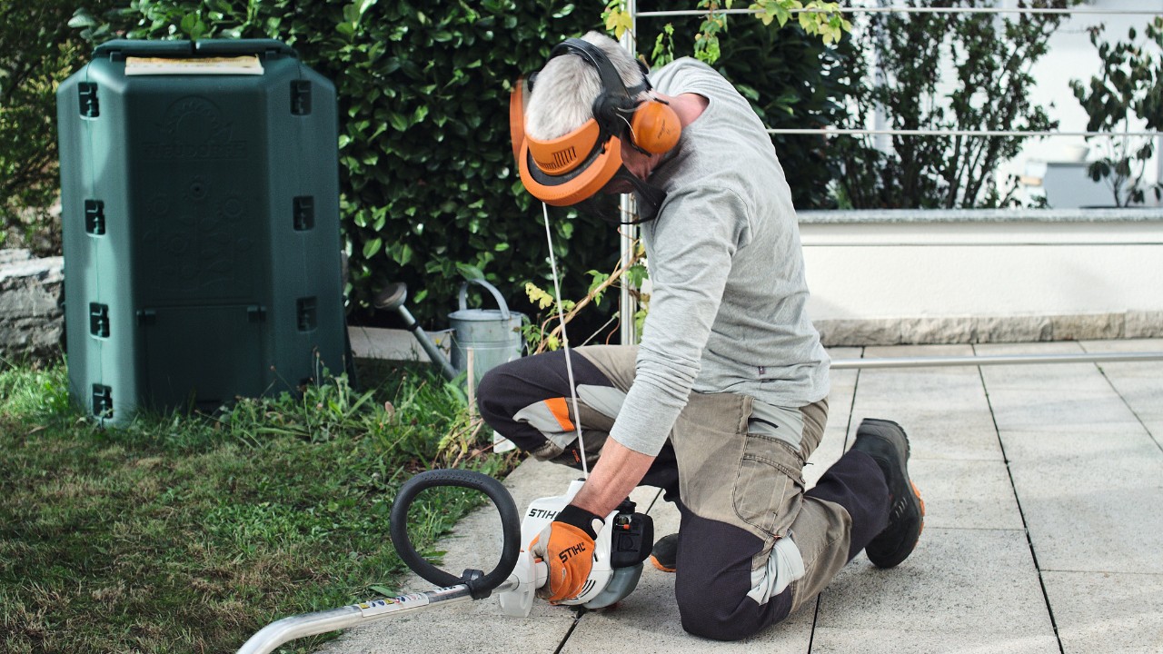 Persona con ropa de protección tira de nuevo de la cuerda de arranque de la desbrozadora de gasolina STIHL FS 38