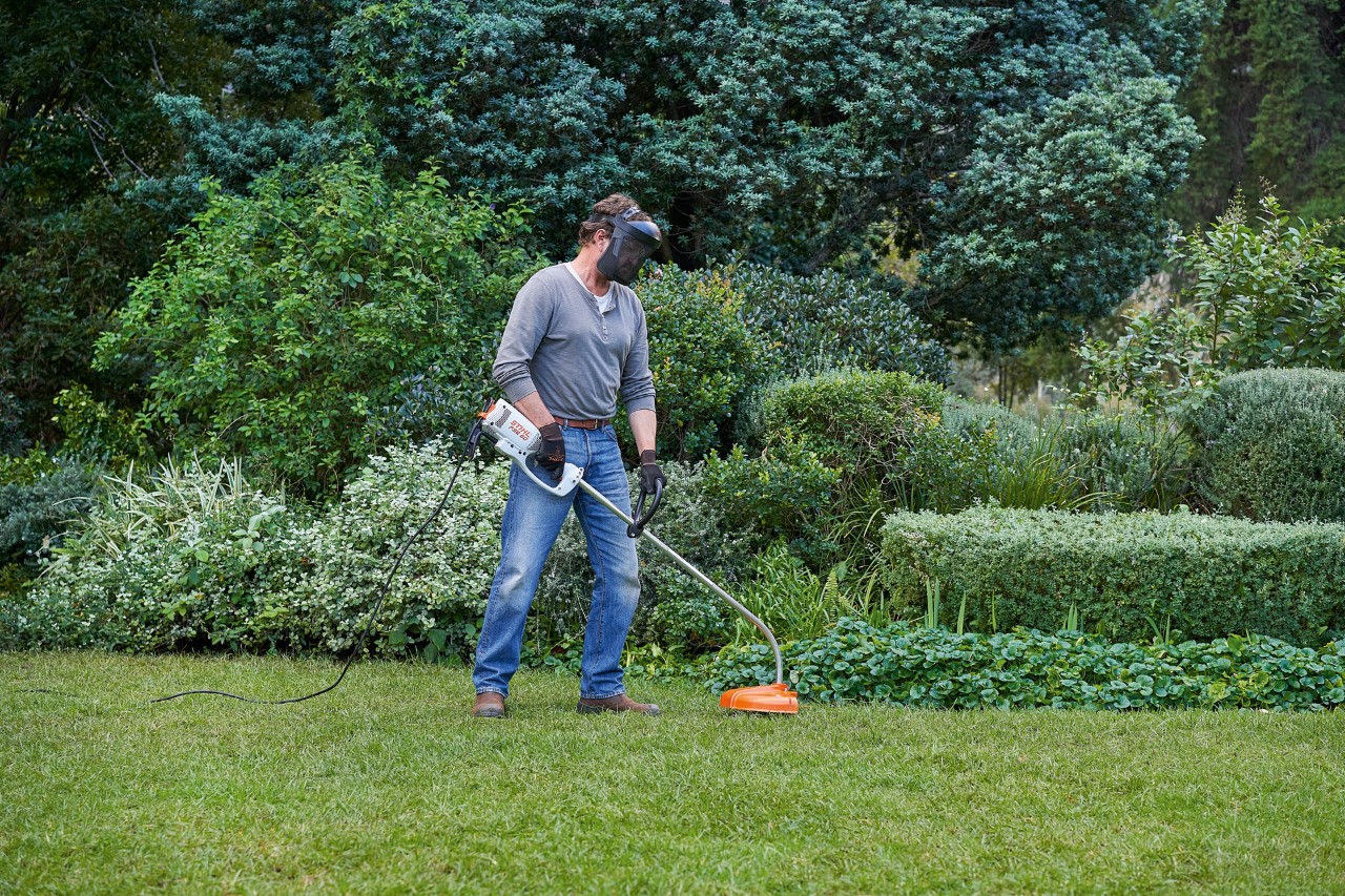 Un hombre con una desbrozadora eléctrica STIHL FSE 60 adopta una postura segura