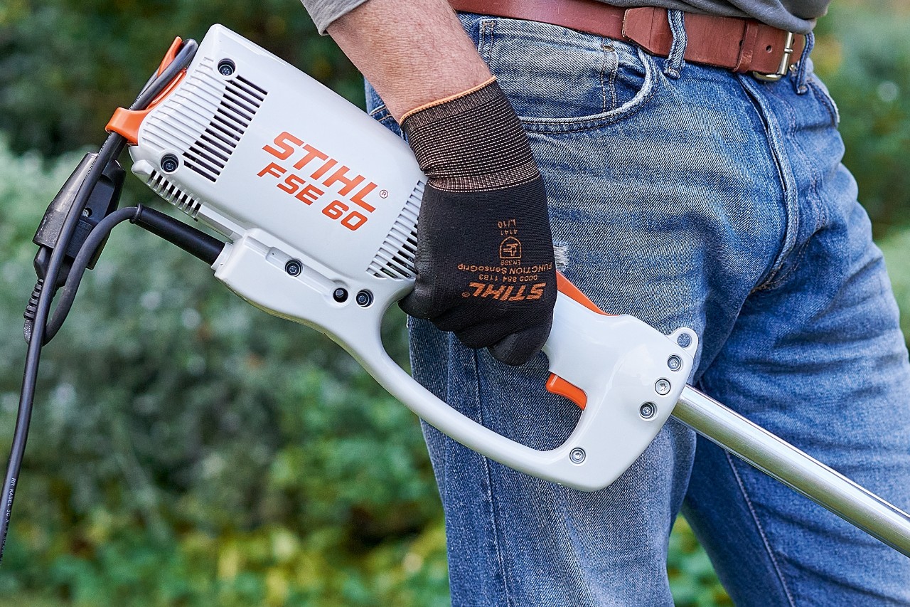 El hombre pulsa el interruptor para apagar la desbrozadora eléctrica STIHL FSE 60.
