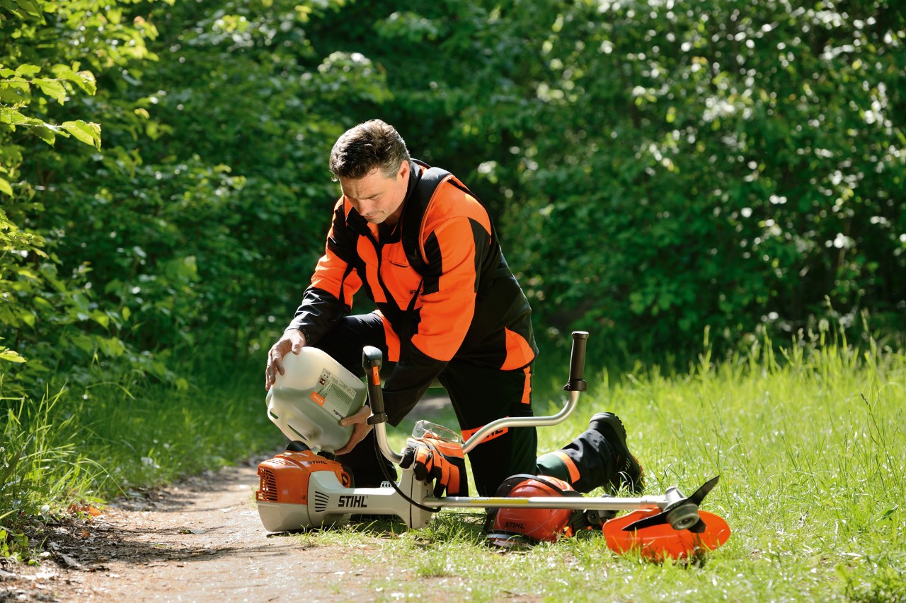 Un hombre reposta la desbrozadora STIHL con una mezcla de gasolina y aceite. 