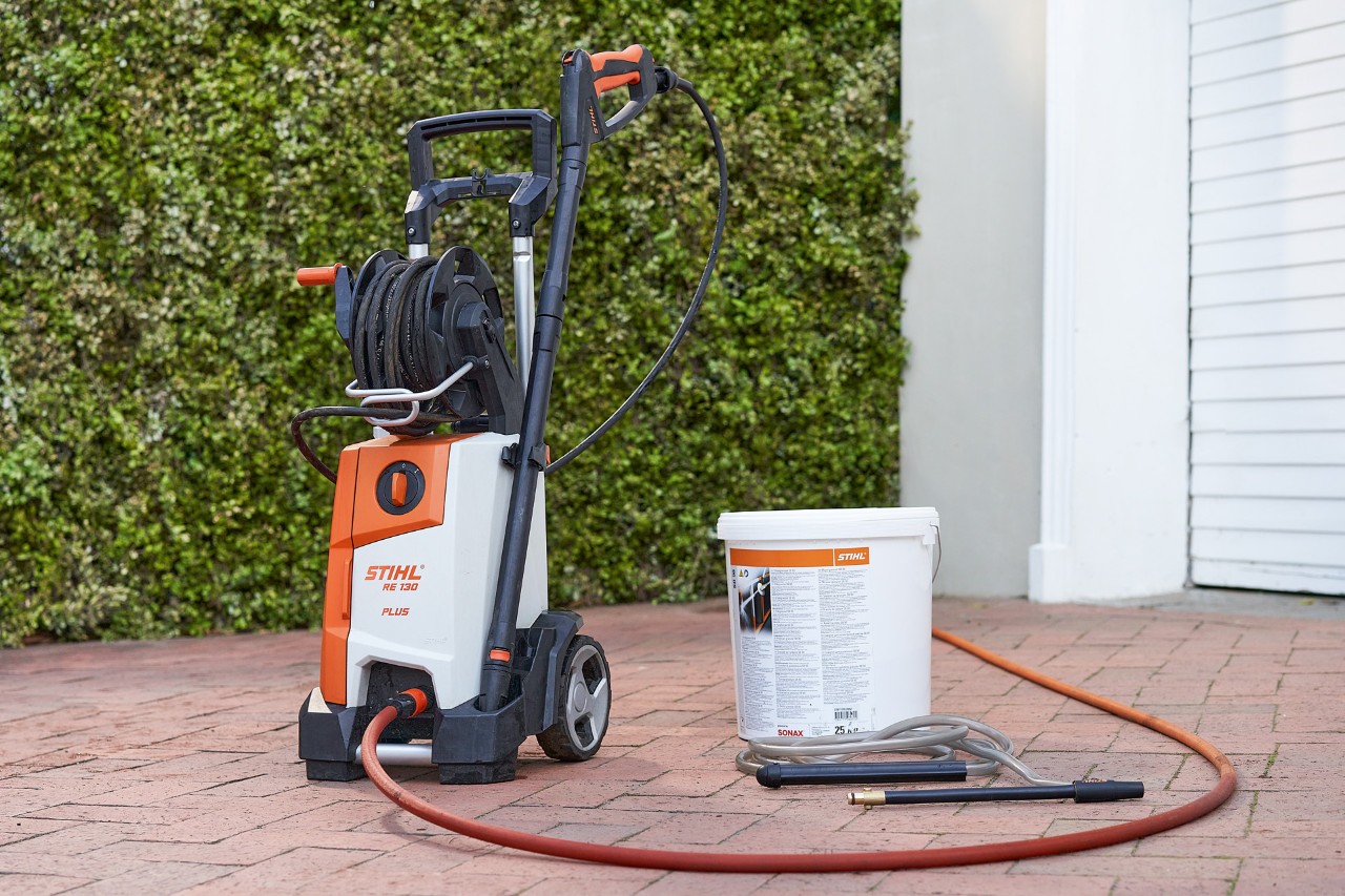 Hidrolimpiadora STIHL RE 130 PLUS y granulado de pulverización SB 90 para hidroarenado delante de un garaje 