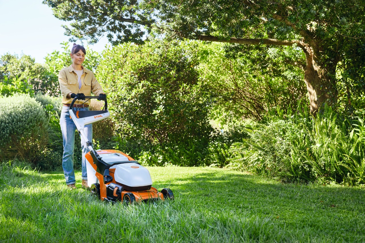Una mujer corta el césped con un cortacésped de batería STIHL RMA 448 PV