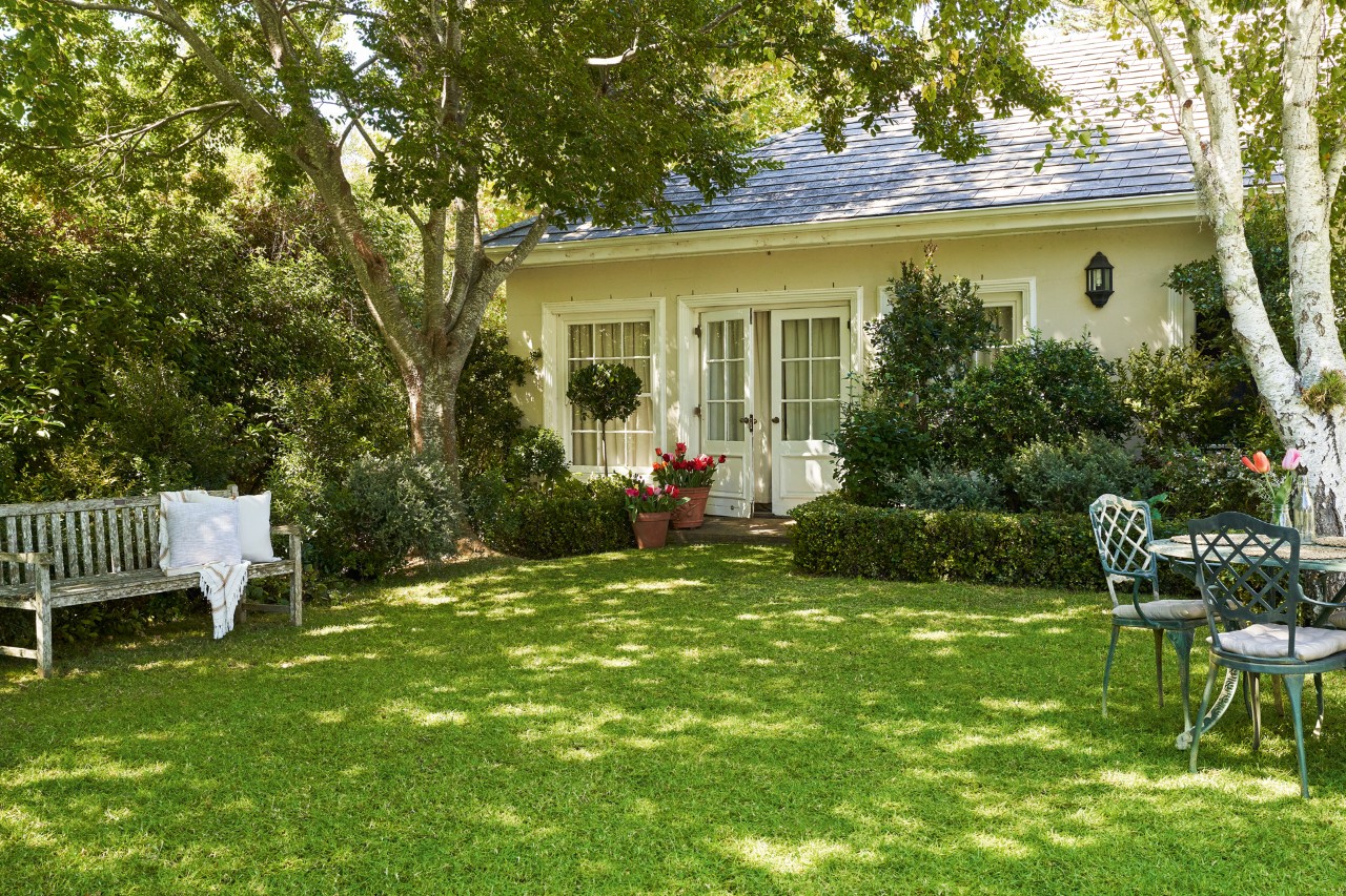 Jardín con césped verde y sano después del encalado, con una casa al fondo