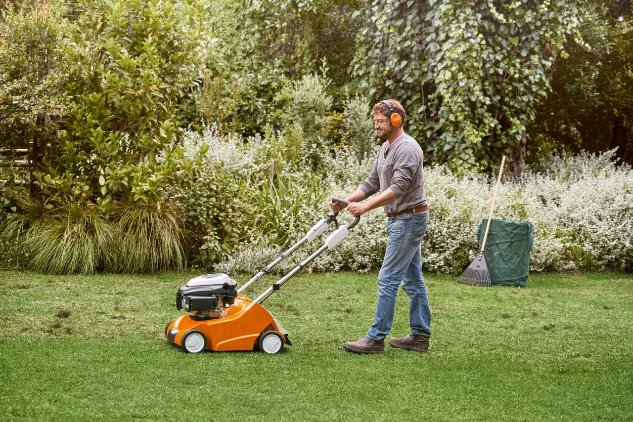 Un hombre escarifica el césped verde con un escarificador STIHL RL 540.
