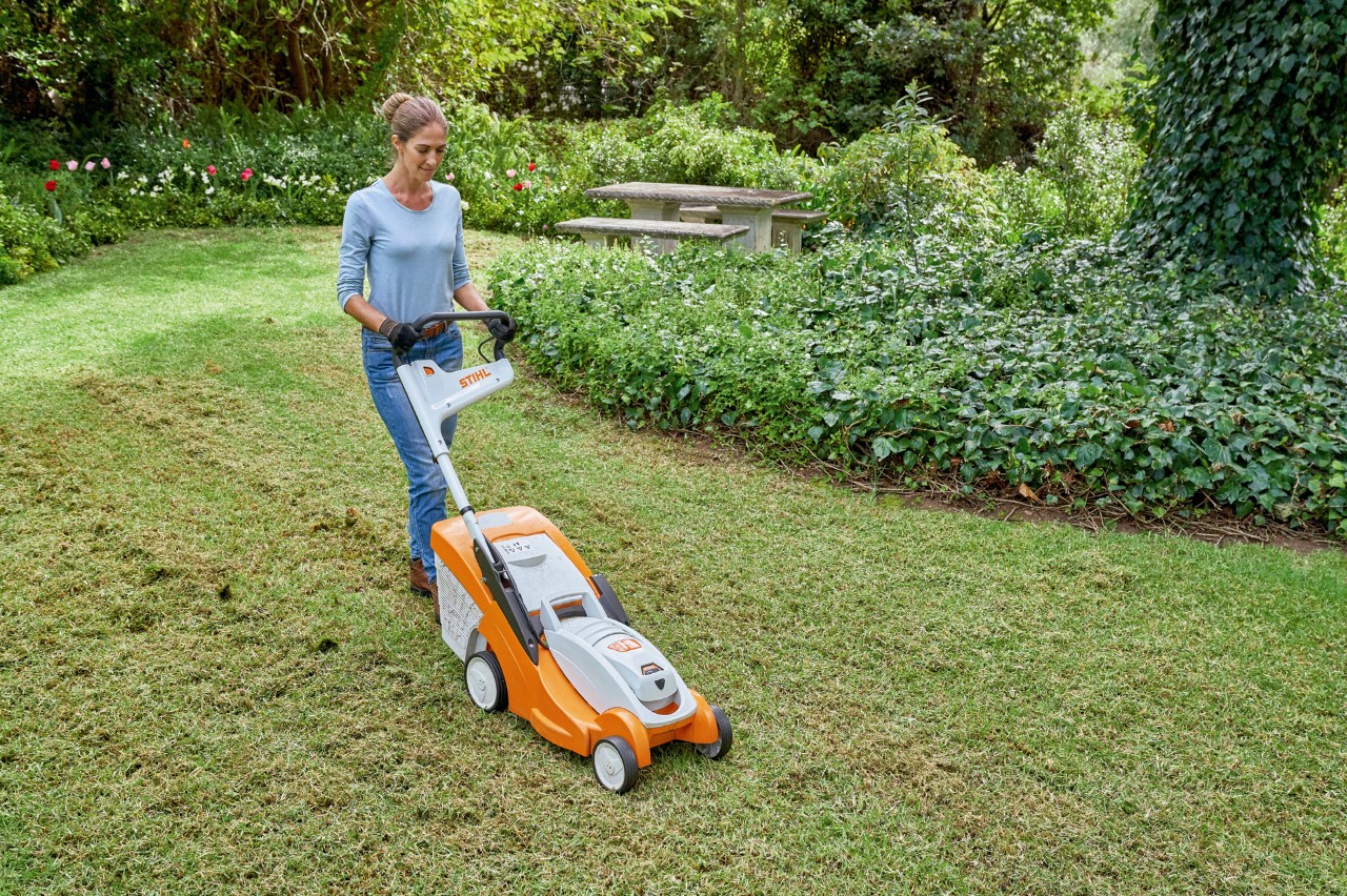 Una mujer usa un cortacésped de batería STIHL RMA 339 C renovar el césped.