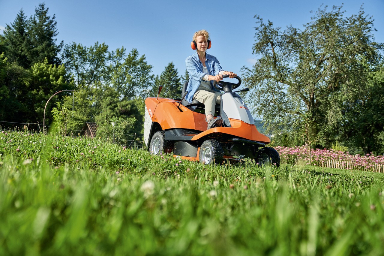 Una mujer corta el césped en una pendiente con un tractor cortacésped STIHL RT 4082 