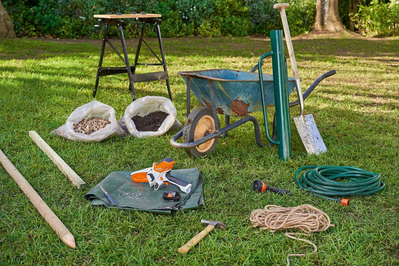 El material de trabajo para la plantación de árboles está en el césped, incluida la podadora de batería STIHL GTA 26.