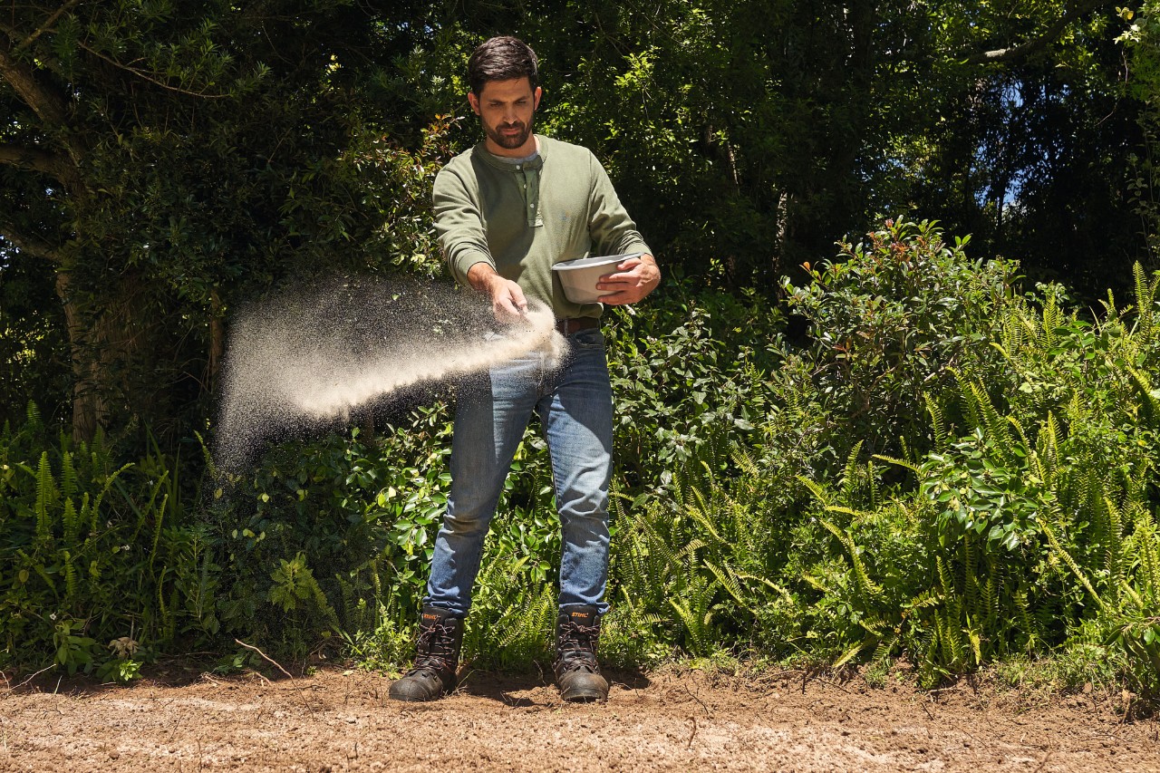 Un hombre esparce semillas en un campo de flores silvestres  