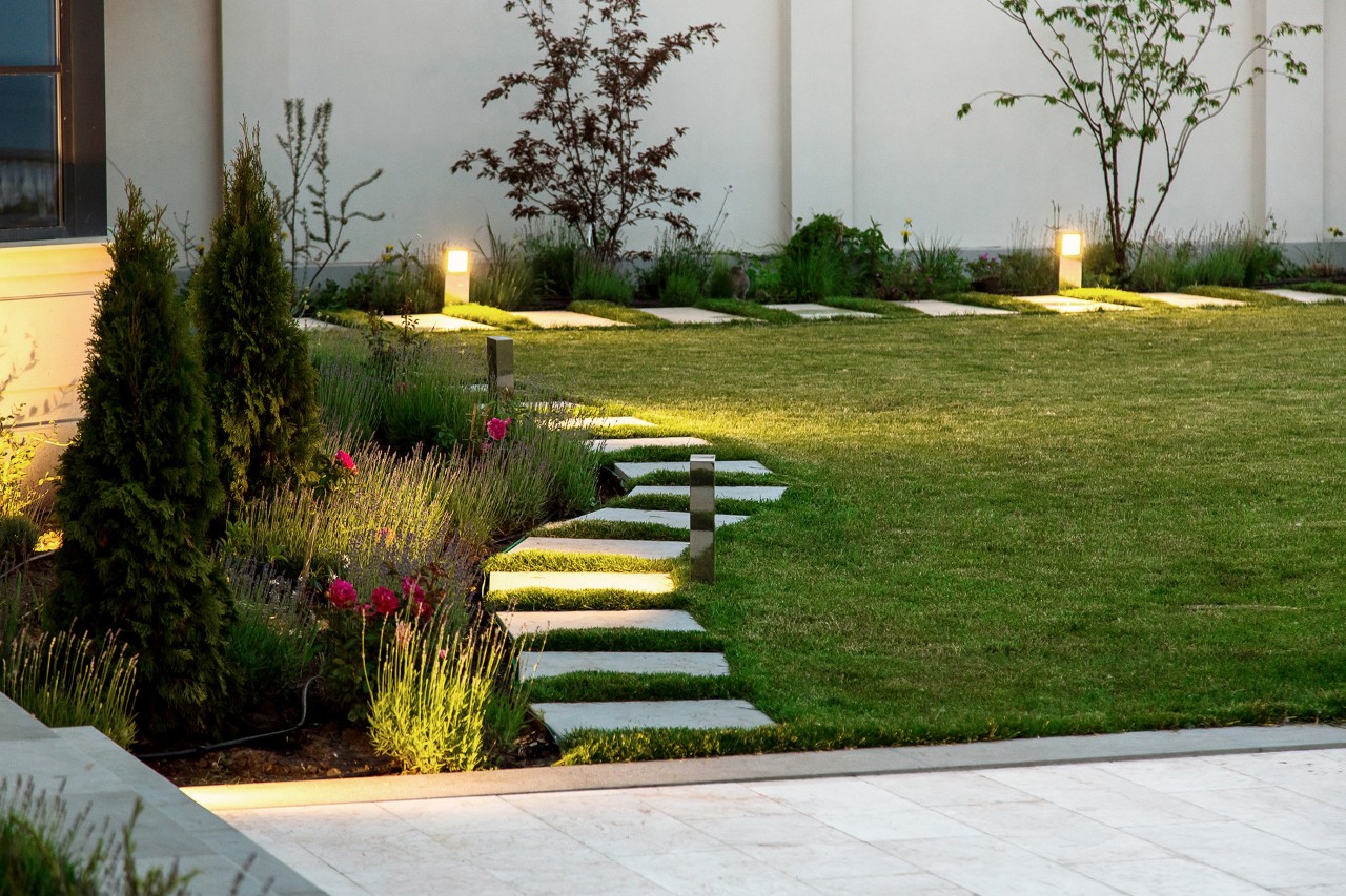 Jardín pequeño, arriates de flores, césped, pasarela de mármol de baldosas cuadradas,  lámpara de pie decorativa.