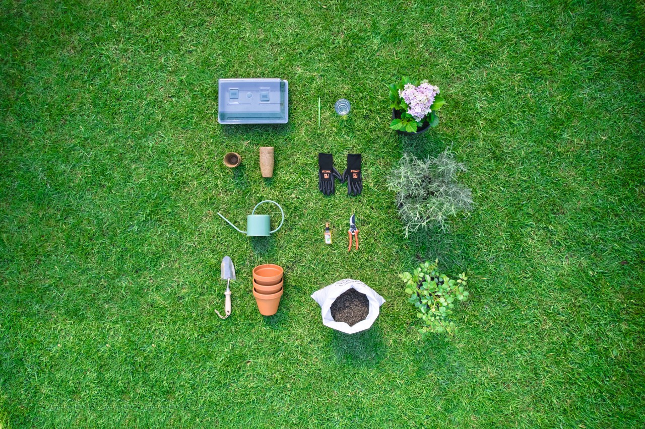 Herramientas y materiales cortar y plantar esquejes: tijeras de jardinero, guantes, tierra, pala, macetas y regadera.