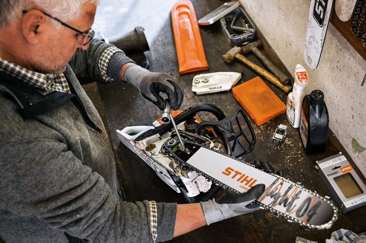Un distribuidor especializado STIHL realiza el mantenimiento de una motosierra con espada STIHL Light 04 y cadena de aserrado Oilomatic