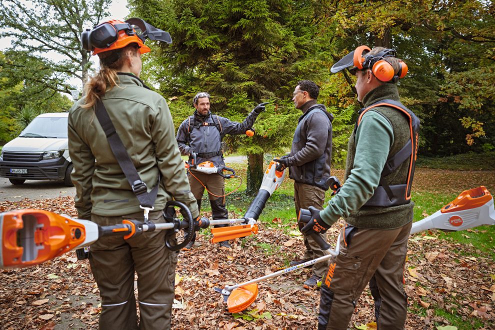 Un grupo de jardineros con máquinas stihl charlan mientras se reparten el trabajo