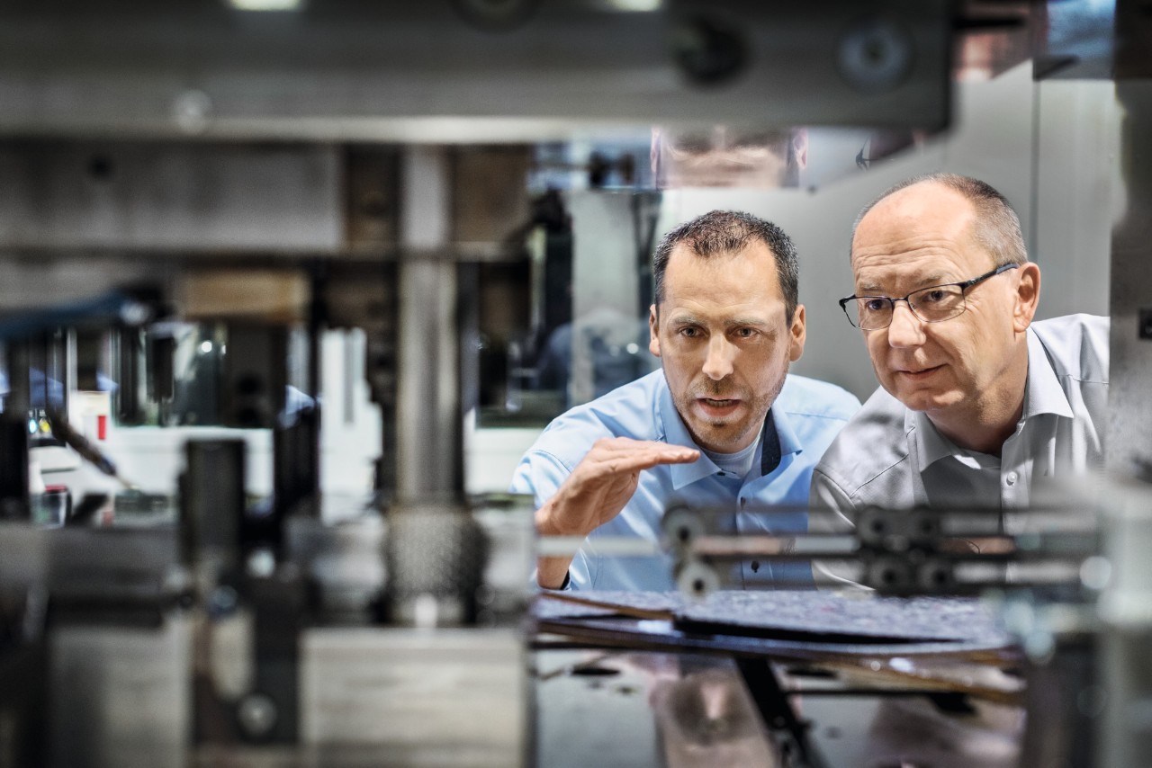 Dos hombres observan una instalación en la fábrica de cadenas