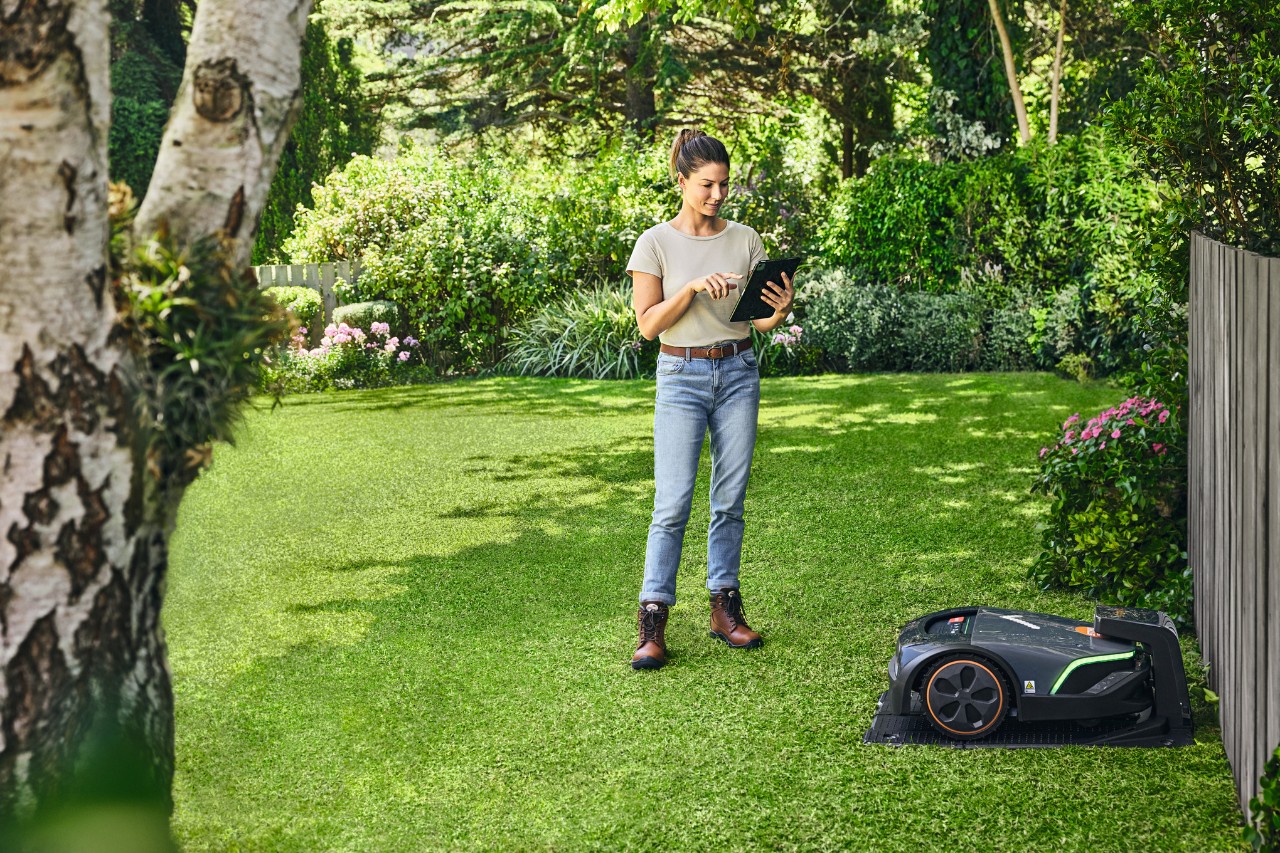 Mujer utilizando el STIHL iMOW® EVO a través de una tablet en su jardín