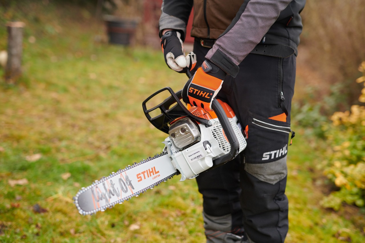 Hombre con equipo de protección sujetando una motosierra de gasolina STIHL con ElastoStart y espada Light 04