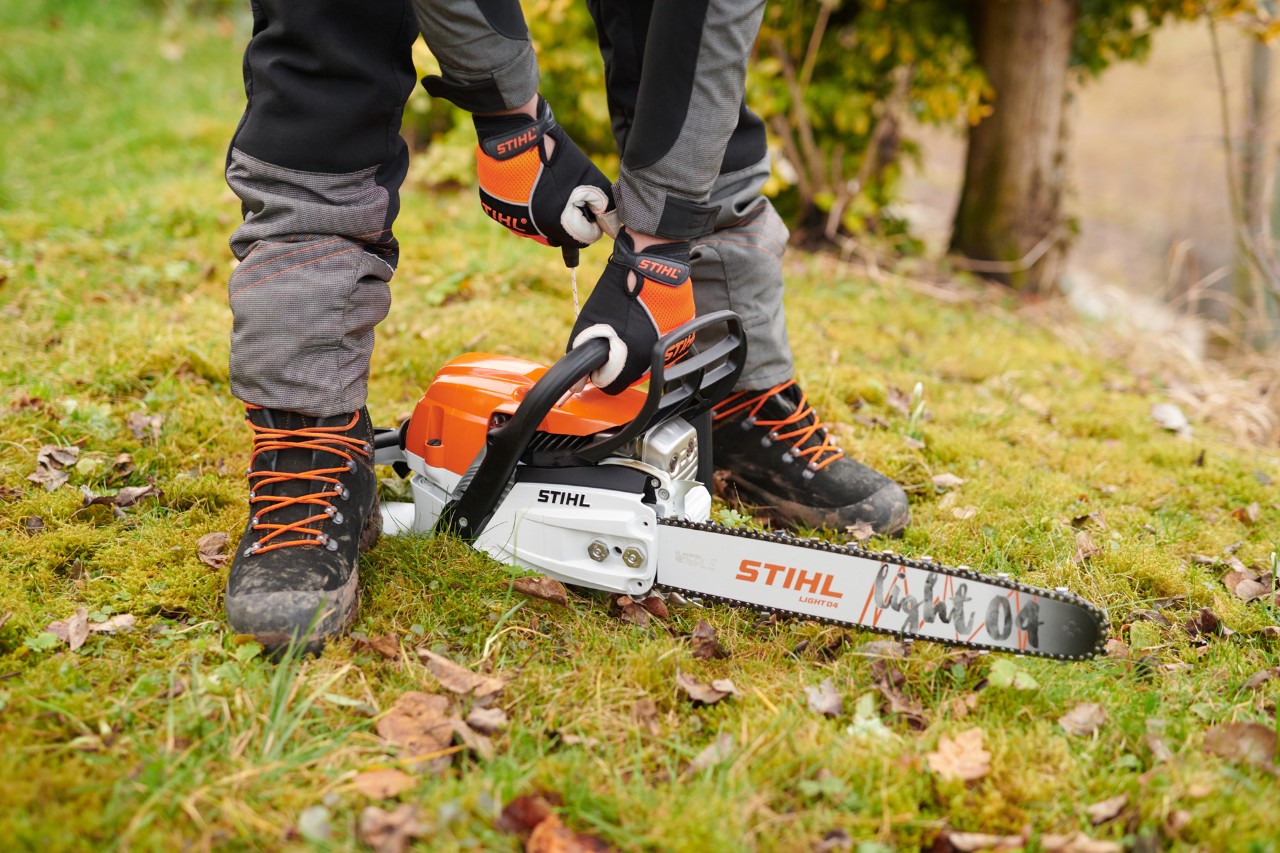 Una motosierra de gasolina STIHL MS 261 C-M siendo arrancada en el suelo