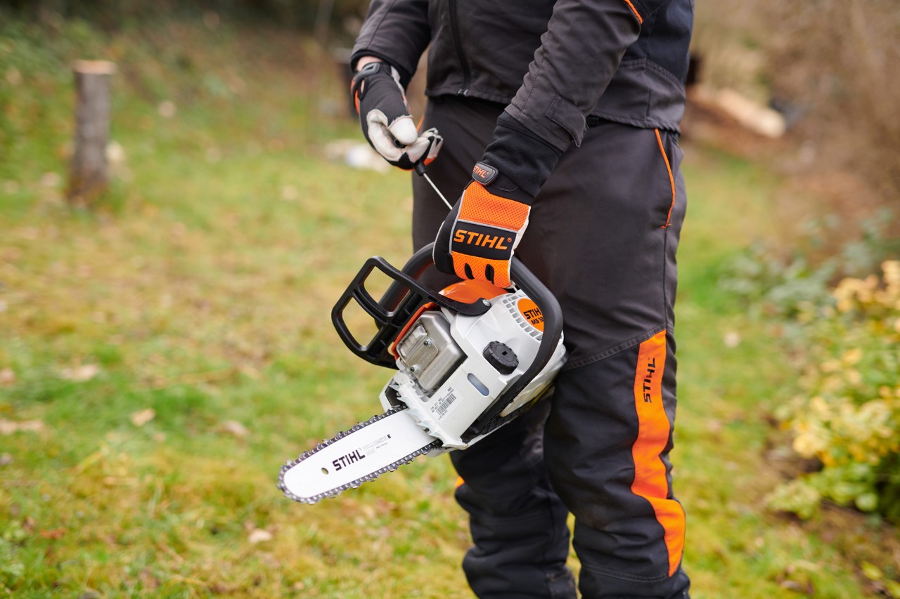 Una persona con equipo de protección sosteniendo una motosierra STIHL de arranque fácil modelo STIHL 180 C-BE 