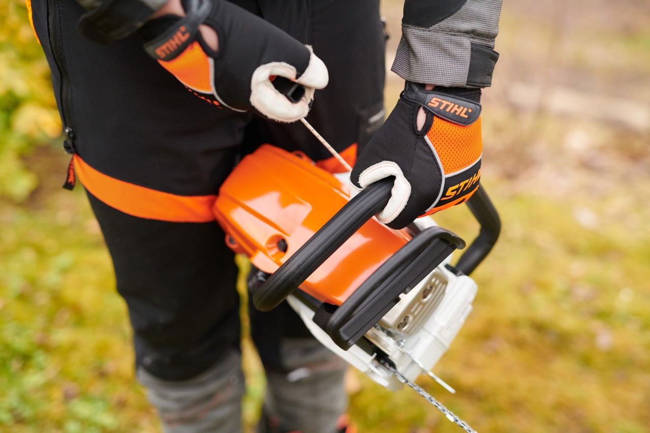 Un usuario con equipamiento de protección pone en marcha una motosierra de gasolina STIHL MS 261 C-M 